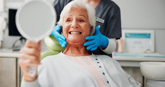 Older woman in dental chair sitting up and smiling